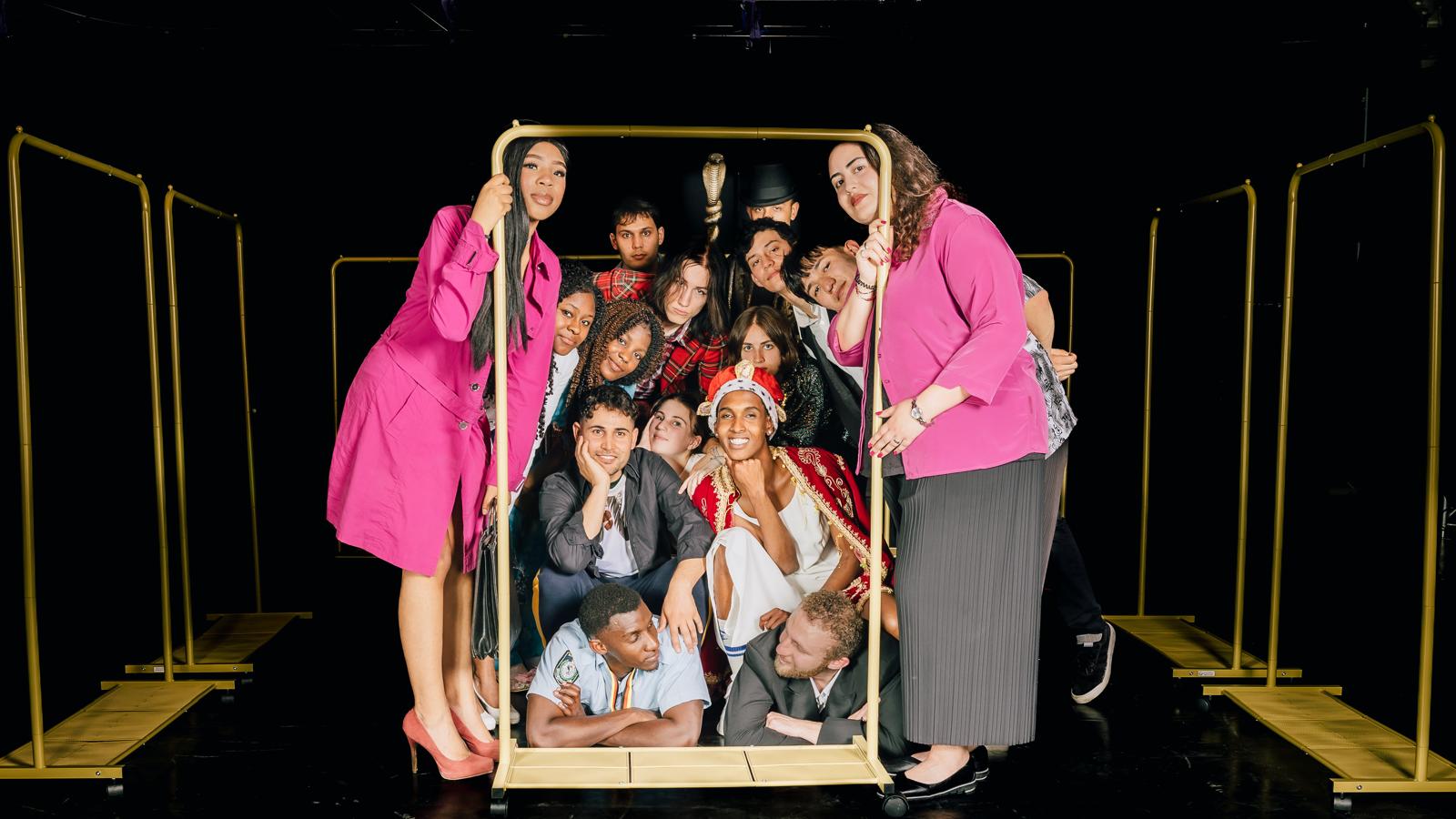 Das Bild zeigt mehrere kostümierte Personen auf der Bühne posen. 