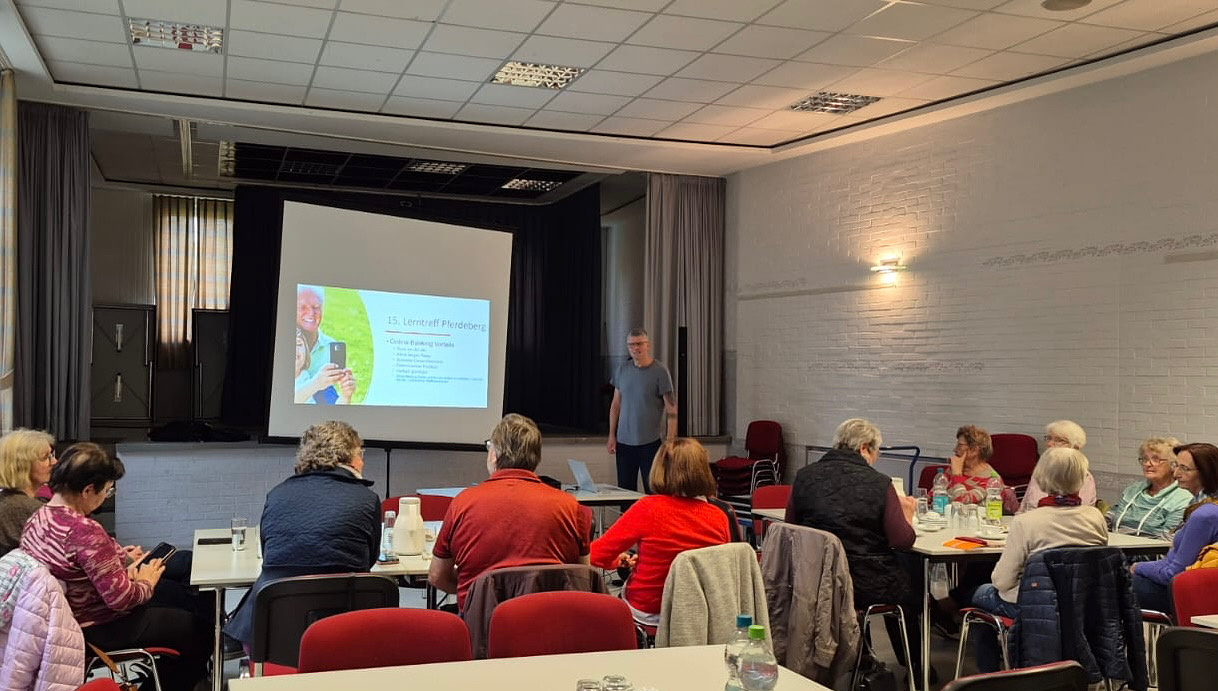 Das Bild zeigt eine Gruppe an Personen, die auf eine Leinwand schauen.