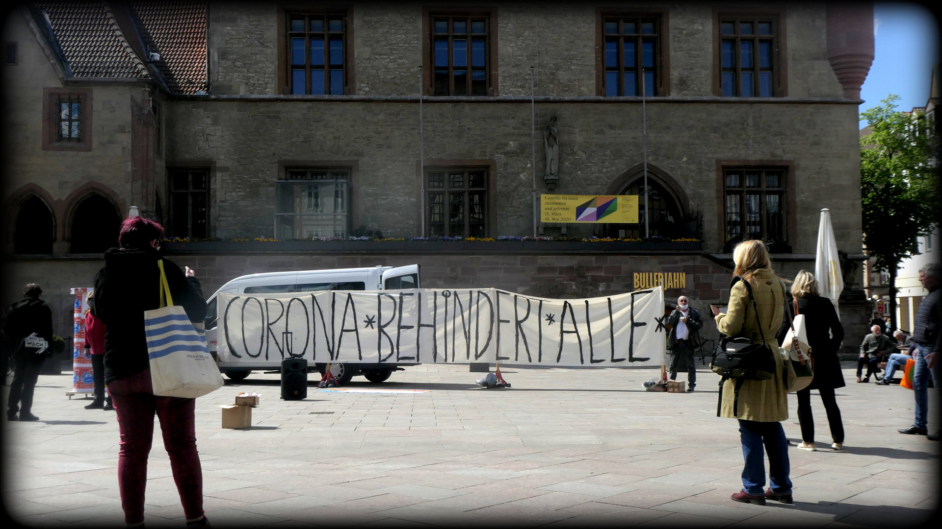 Menschen mit Transparent vor dem alten Rathaus in Göttingen. Aufschrift: "Corona behindert alle".