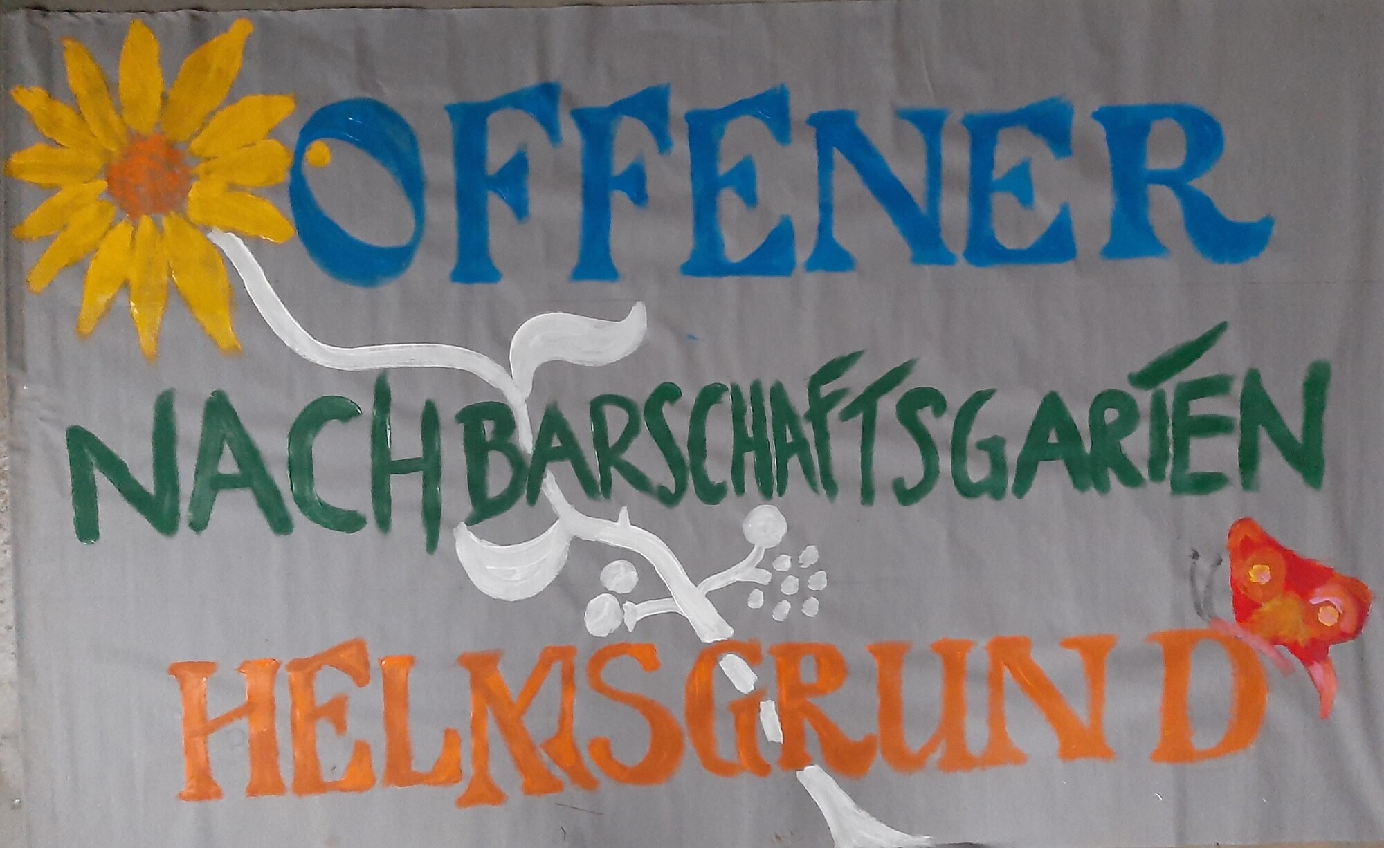 Auf dem Bild ist ein Bauwagenschild abgebildet mit der Aufschrift: offener Nachbarschaftsgarten Helmsgrund.