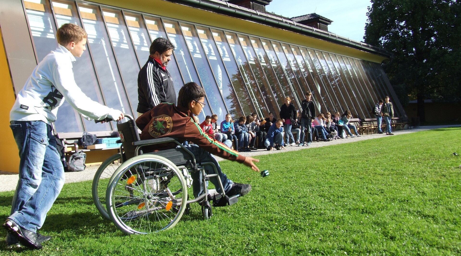 Kind im Rollstuhl spielt auf einem Sportplatz (Bild von Stefan Schranz auf Pixabay)
