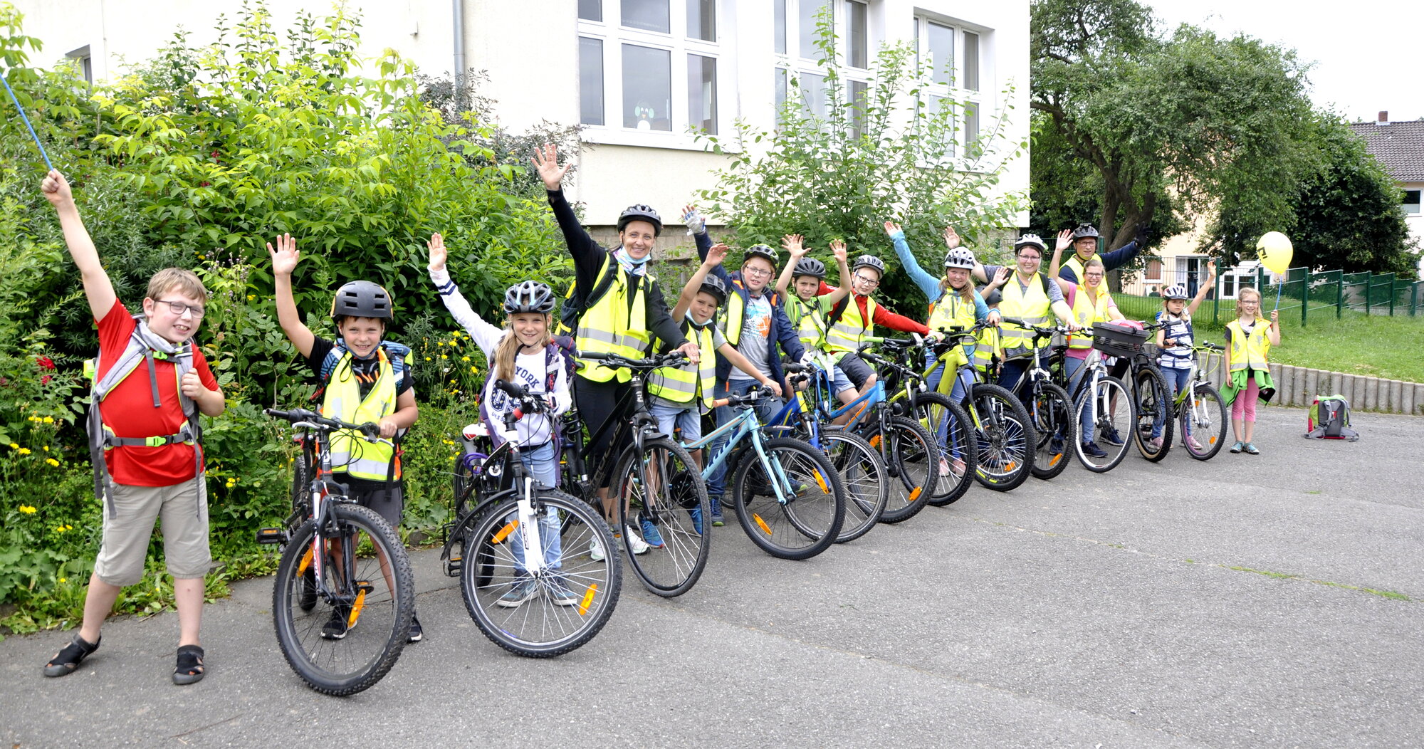 Kinder und Erwachsene posieren mit Fahrrädern und Warnwesten