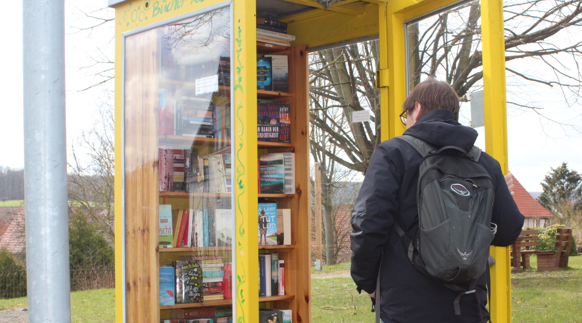 Ein Mann steht vor einer offenen Bücherzelle