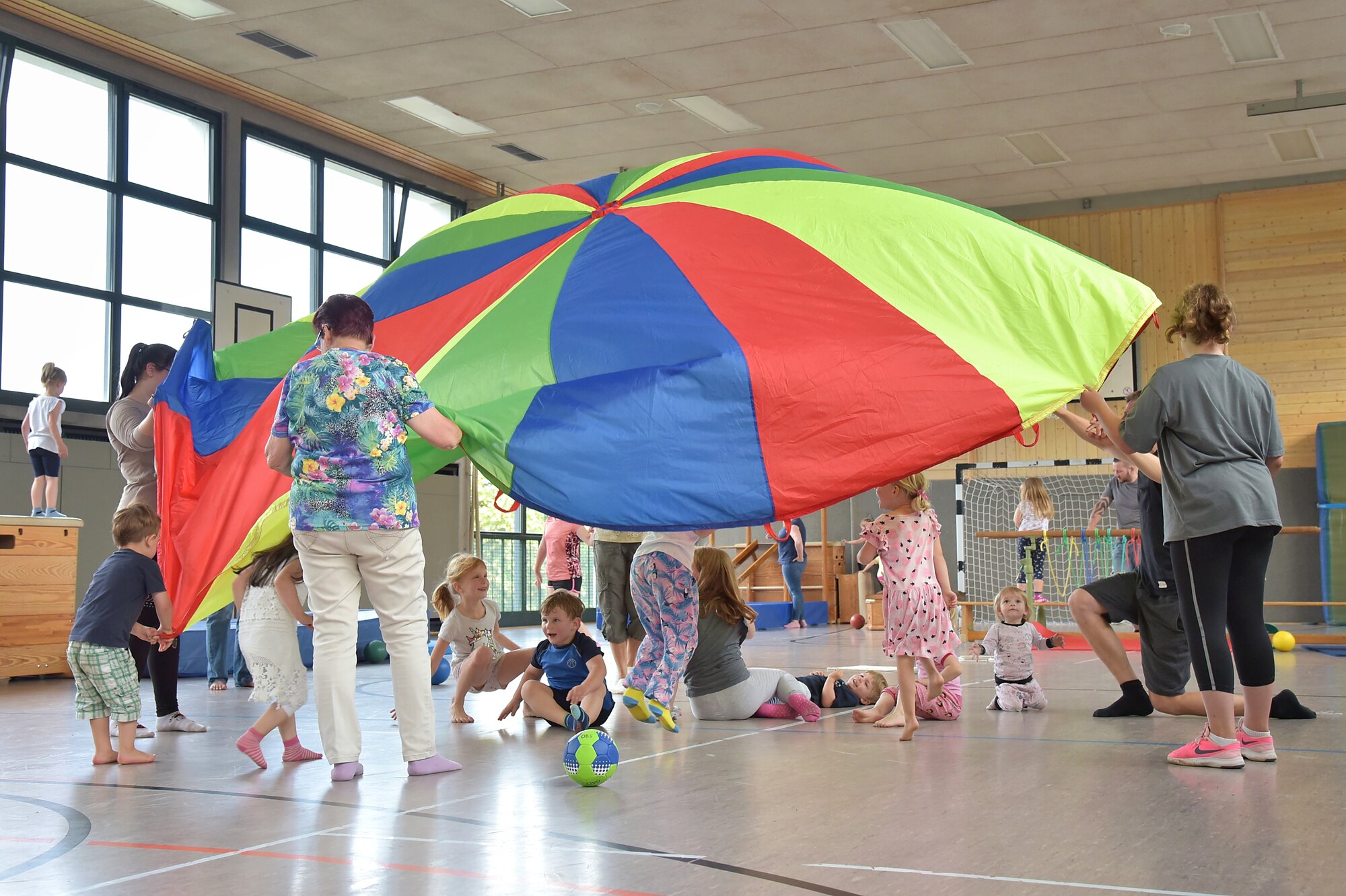 Kinder und Erwachsene mit Schwungtuch in einer Sporthalle