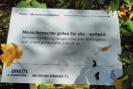 Das Bild zeigt einen Wegweiser am Eingang zum Plesse-Menschenrechtspfad.
