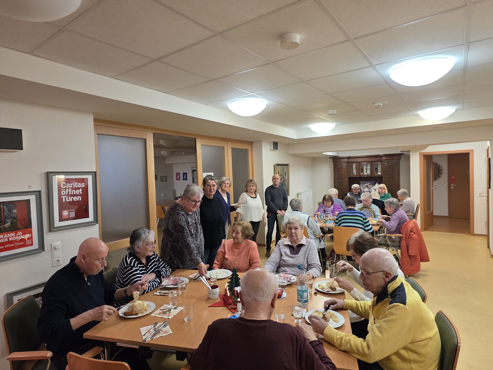 Das Bild zeigt einen Mittagstisch, an dem mehrere Personen sitzen und essen.