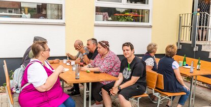 Gemütliches Beisammensitzen bei Bratwurst, hausgemachten Salaten sowie Kaffee und Kuchen beim Quartier-Sommerfest „Aktionstag Aue“ in der Tagesstätte Lindenhof