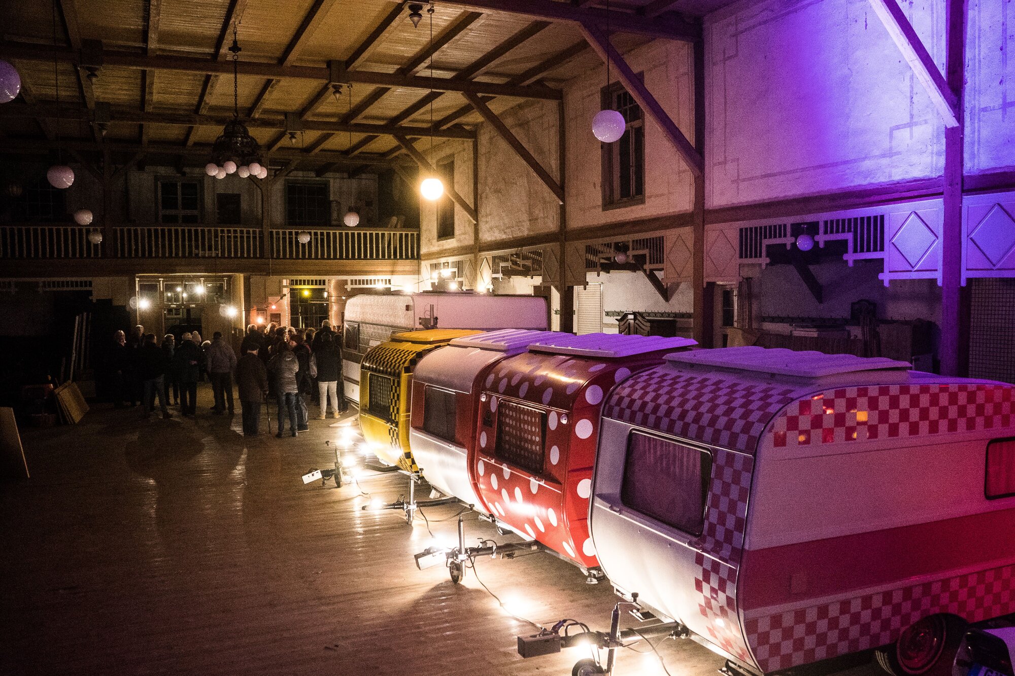 Wohnwagen und Menschen in alter Halle mit buntem Licht