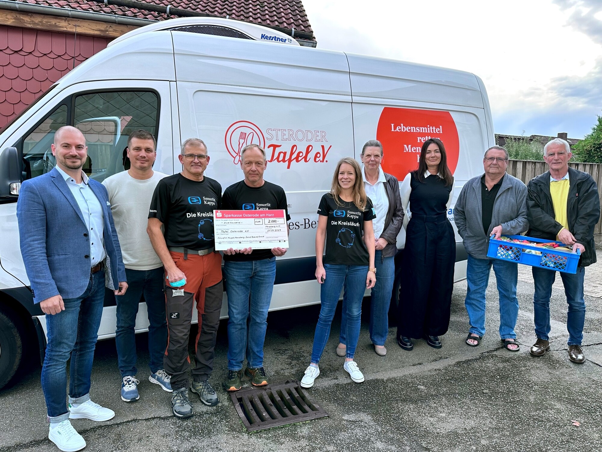 Das Bild zeigt ein Fahrzeug der Osteroder Tafel und Menschen, die davor stehen.