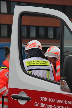 Das Bild zeigt drei Personen des DRK hinter einer Autotür stehend.