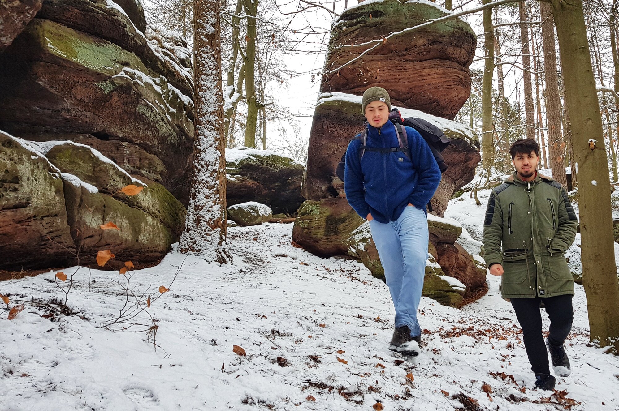2 Männer gehen im schneebedeckten Wald spazieren